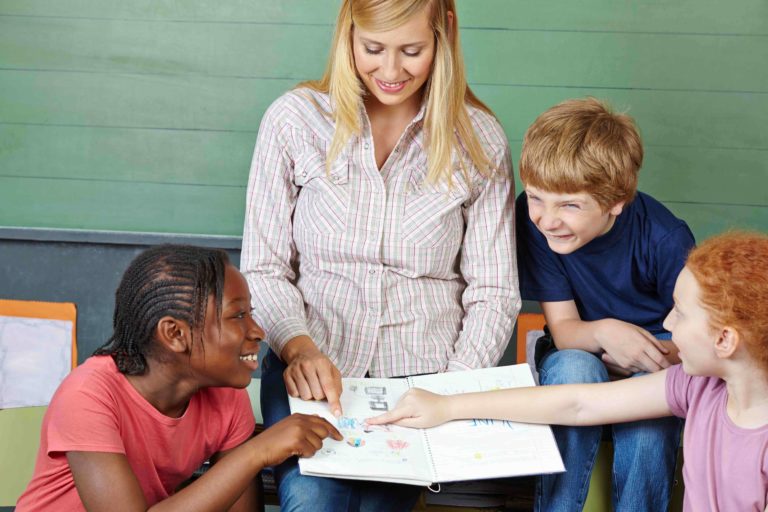 Female teacher showing students drawings in a notebook