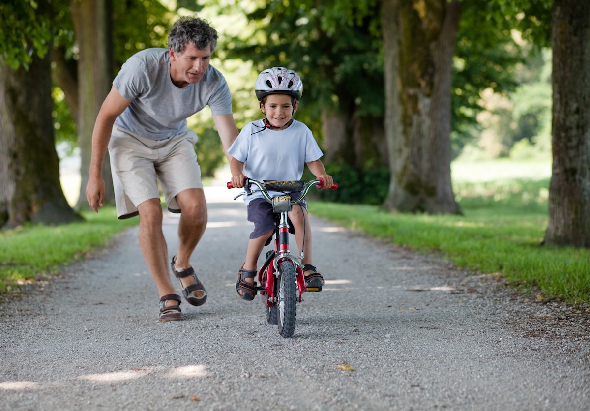 A father teaching his young son how to ride a bike