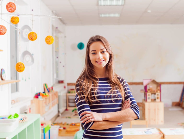 Young female teacher standing at the front of a elementary classroom.