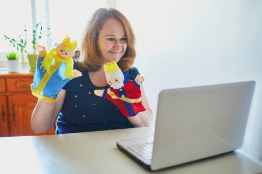 Teacher holding up puppets while on a Zoom video call.