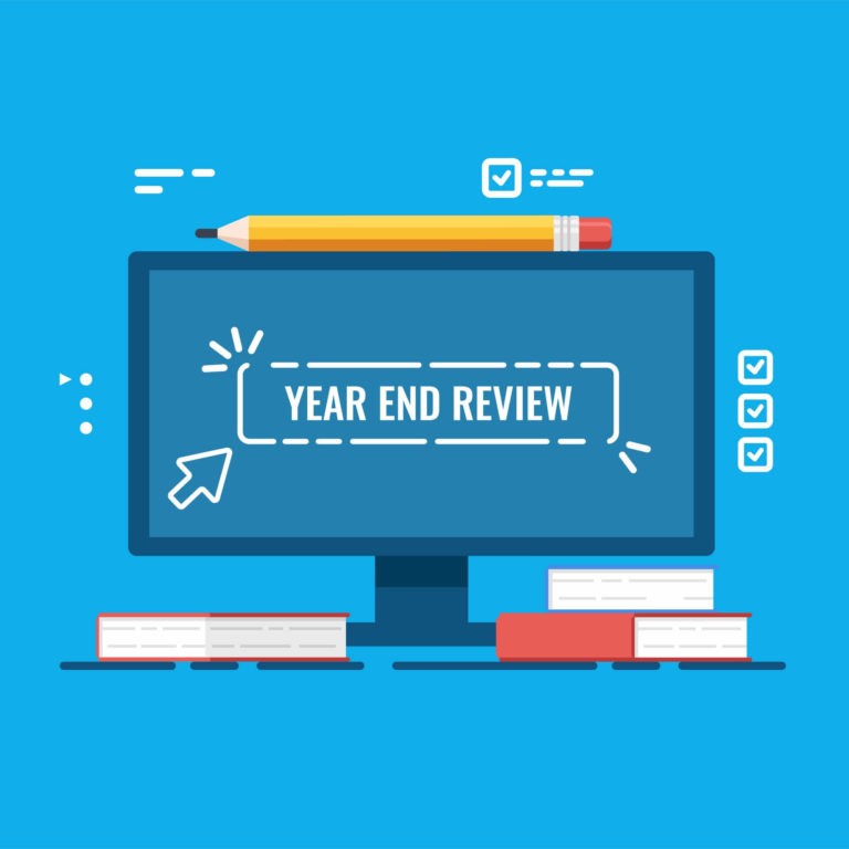 Computer screen with the words ‘Year End Review’ surrounded by books and a pencil