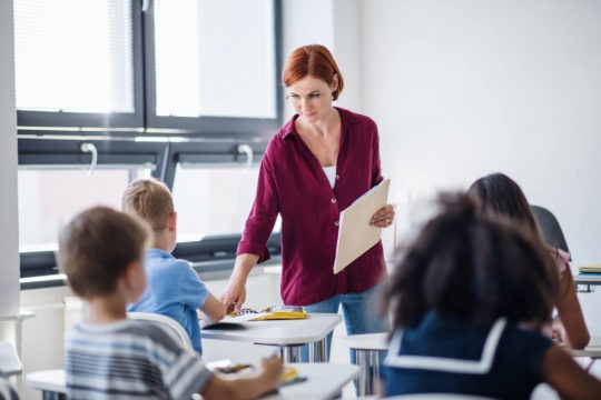 Teacher walking around her classroom full of young students.