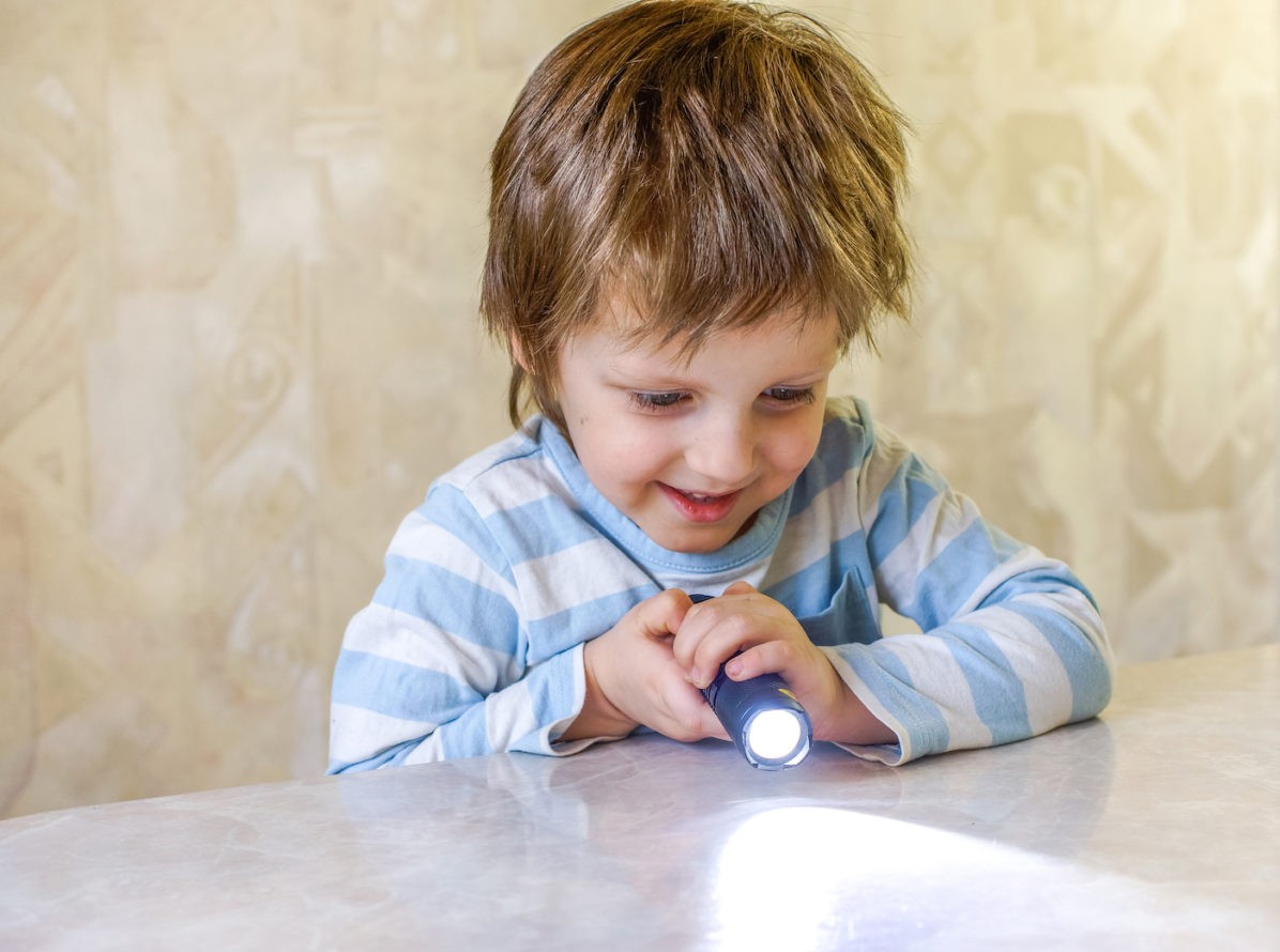 Young boy shining flashlight on a table