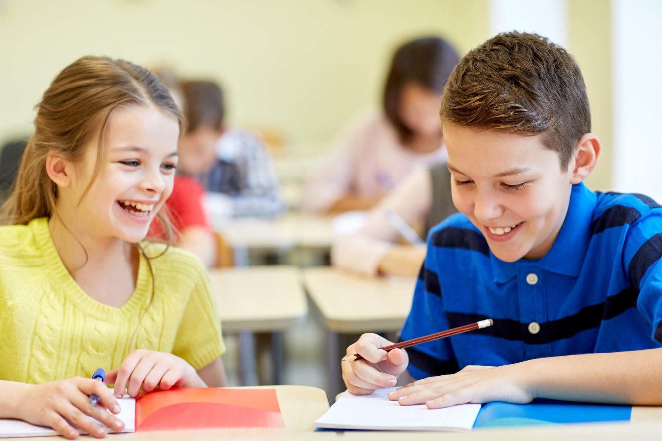 Two young smiling students working together on an activity