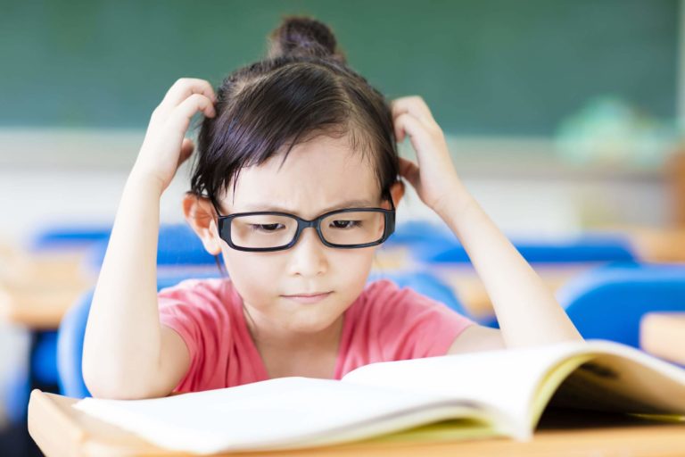 Young, frustrated student sitting at a desk struggling to read.