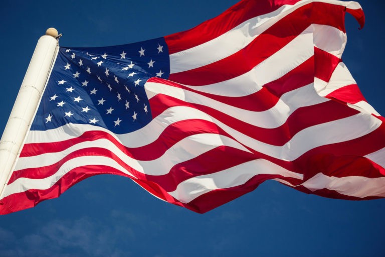 American flag on a flag pole blowing in the wind.