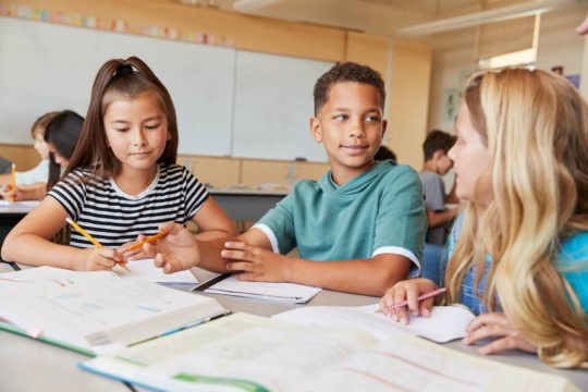 Group of young students working together at a table.