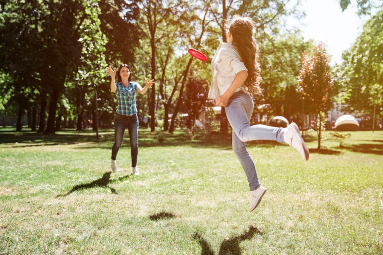 Two older girls outside playing Frisbee.