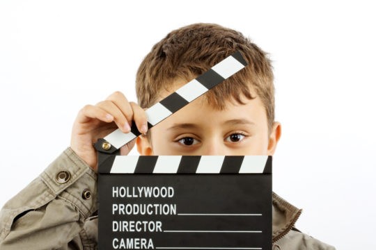 Young boy holding film slate