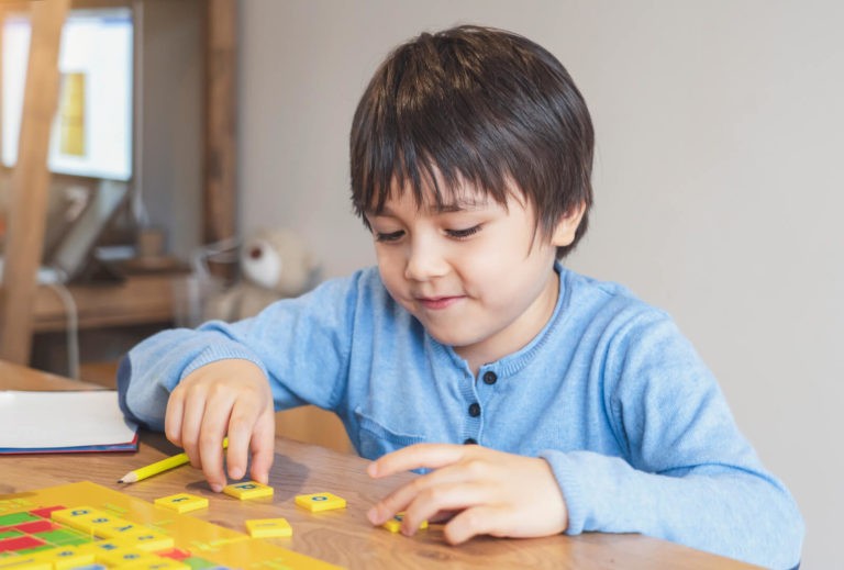 Young boy playing with tiles with letters on them.