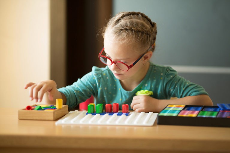 Young girl sitting at a table playing with sensory toys.