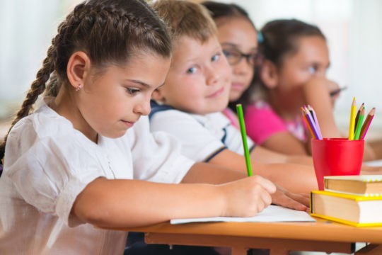 Young girl drawing on paper with colored pencils