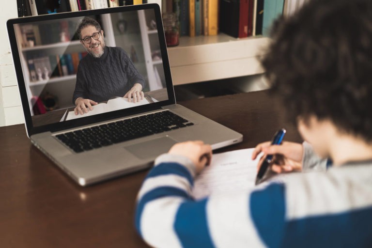 Teacher helping a young student over a zoom call.