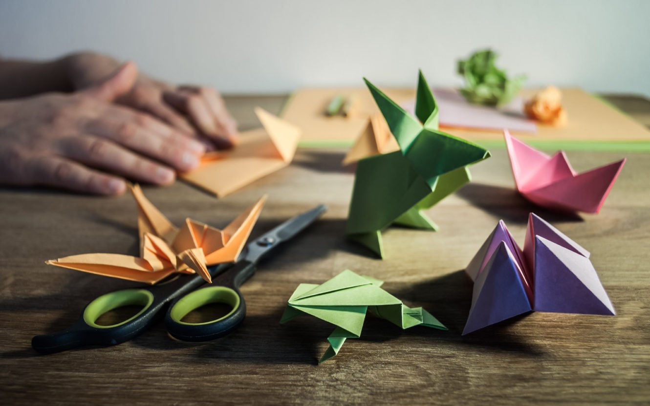 Person folding different colored pieces of paper into origami