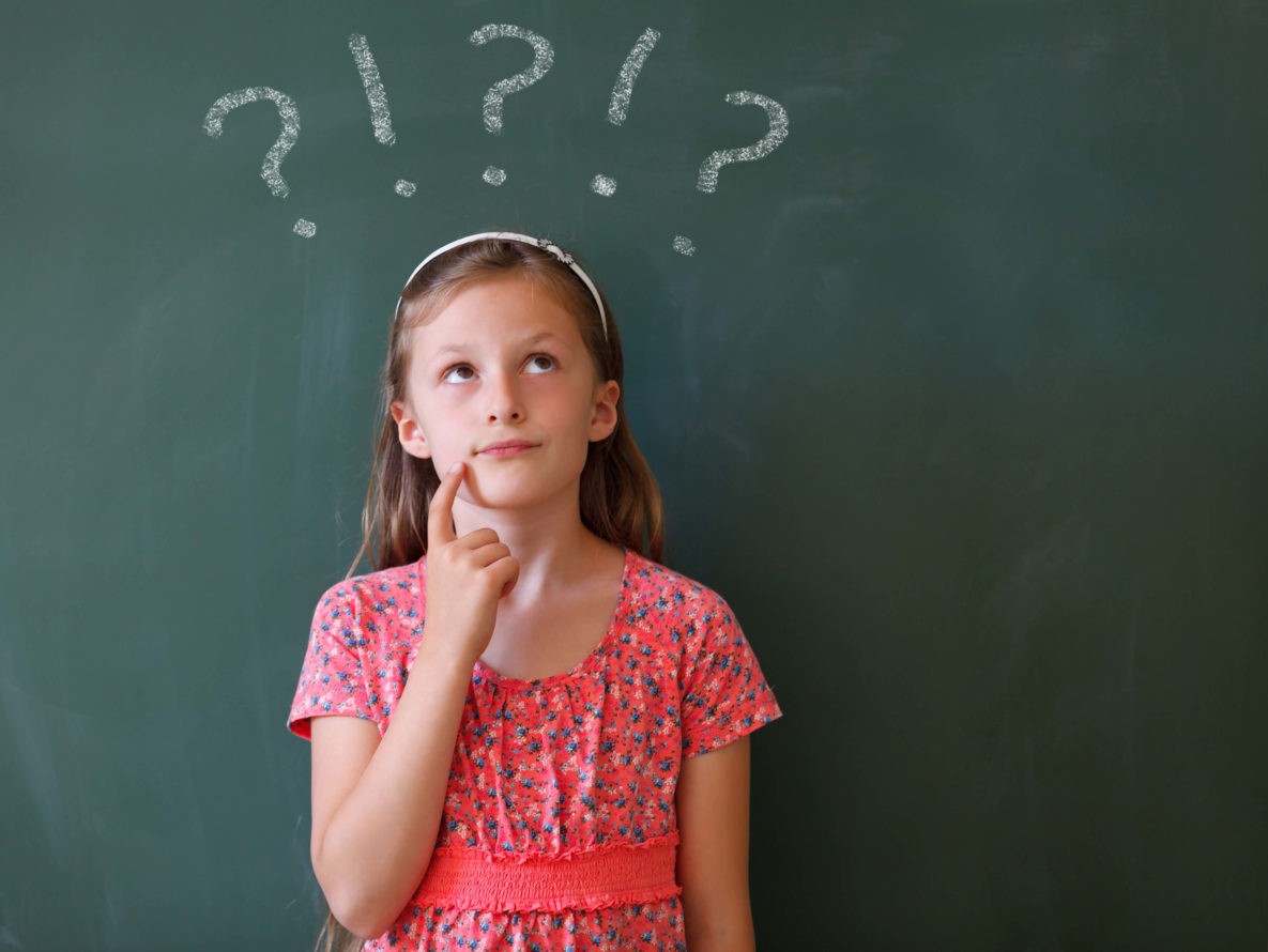 Young girl standing in front of a chalkboard thinking