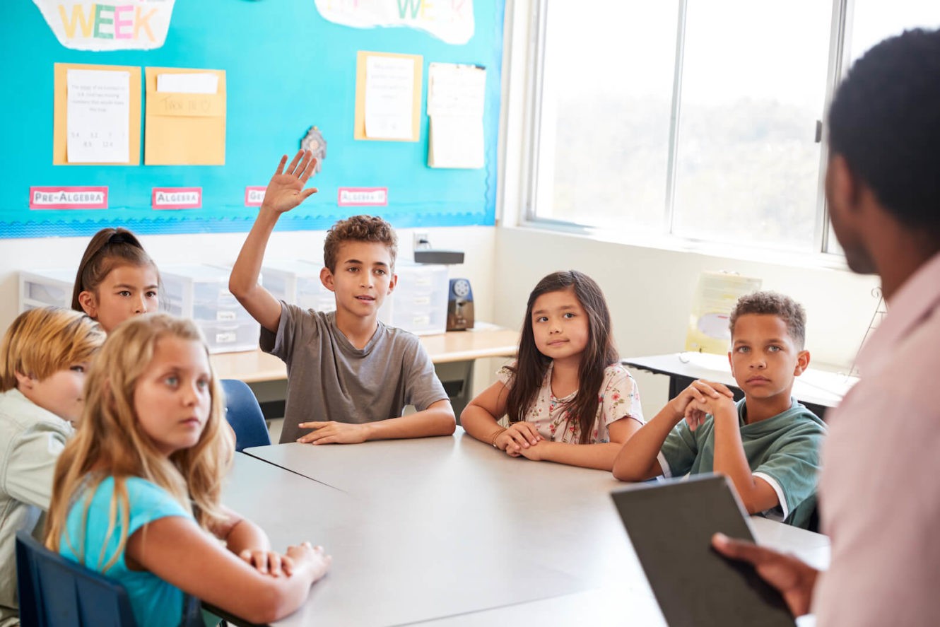 Young boy raising his hand in a classroom