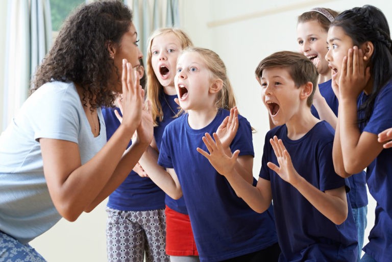 Group of students mimicking a teacher as she demonstrates.