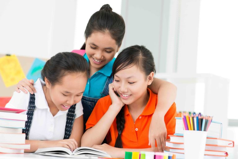 A group of female students reading a book together