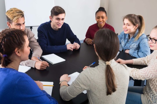 A group of high school students sitting around a circle working together