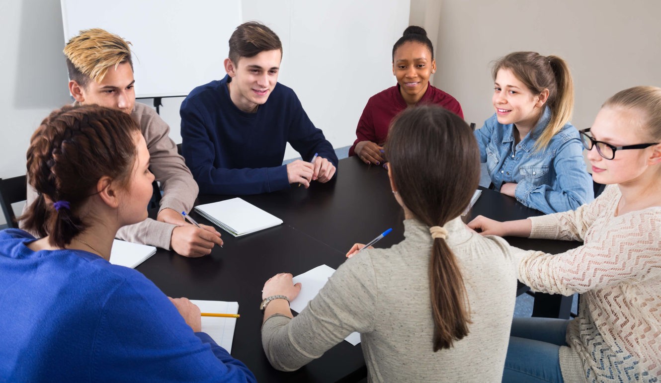 A group of high school students at a table having a discussion